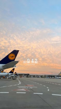 two airplanes are parked on the tarmac at an airport as the sun is setting