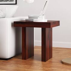 a white couch sitting next to a wooden table with a lamp on top of it