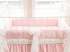 a baby crib with pink and white bedding