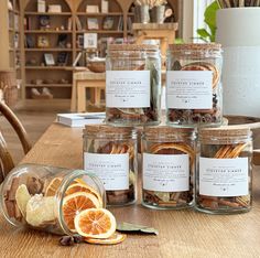 several jars filled with dried fruit and nuts on top of a wooden table next to a potted plant