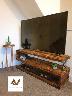 a flat screen tv sitting on top of a wooden shelf next to a planter