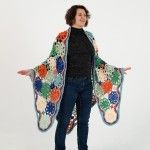 a woman is standing with her arms out in front of the camera and wearing a multicolored shawl