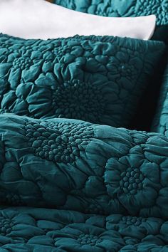 the bed is made with teal colored sheets and pillows