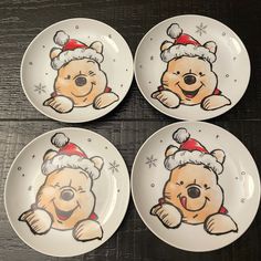 four winnie the pooh plates with santa hats and snowflakes on them