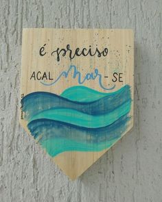 a wooden sign hanging on the side of a building with blue waves painted on it