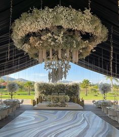 an outdoor wedding venue set up with flowers and chandeliers hanging from the ceiling