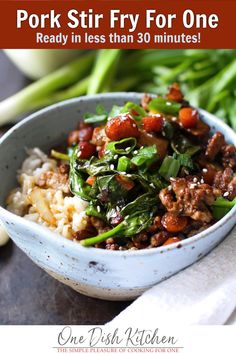 a white bowl filled with meat and vegetables on top of rice next to green beans