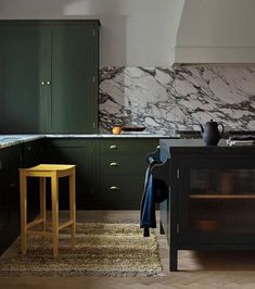 a kitchen with green cabinets and marble counter tops on the walls, along with an area rug