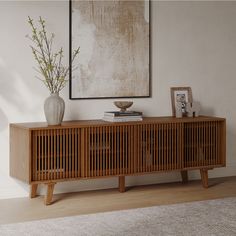 a wooden sideboard with two drawers and a vase on top, in front of a white wall