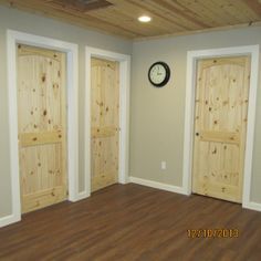 an empty room with three doors and a clock on the wall