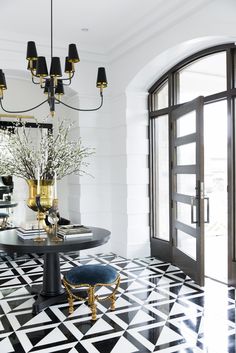 a black and white dining room with chandelier, table, chairs and vases