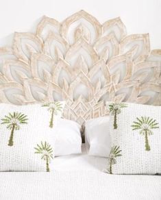 a white bed topped with lots of pillows next to a headboard made out of wood