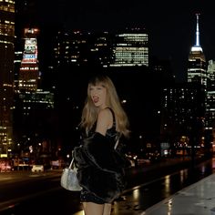 a woman standing in front of a city skyline at night