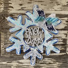 a snowflake ornament hanging on a wooden wall with the word joy written in it