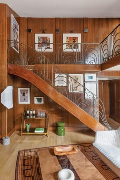 a living room with wood paneling and metal railings on the wall, stairs leading up to the second floor