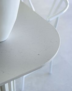 a white vase sitting on top of a table next to two chairs and one chair