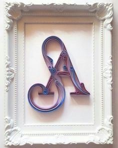 the letter k is made out of metal and sits in a white frame on top of a wall