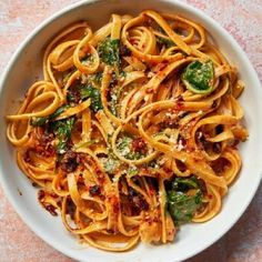 a white bowl filled with pasta and spinach