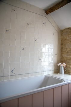 a white sink sitting under a window next to a bath tub in a room with stone walls