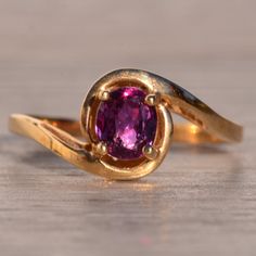 Ocho Calle: Reddish-Purple Natural Sapphire In Yellow Gold Bypass Ring. The Ring Showcases A Central 5.5 Millimeter By 4.5 Millimeter Oval Brilliant Cut Heated Natural Reddish-Purple Sapphire, Radiating Elegance. Complementing Its Beauty, A Bypass Tapered Sweeping Shank Completes The Look With Grace. Crafted In 14 Karat Yellow Gold, This Ring Is Currently A Finger Size 6.25 And Can Be Adjusted For An Additional Charge Upon Request. Classic Purple Ruby Ring, Purple Ruby Ring For Gift, Purple Ruby Rings For Gifts, Purple Ruby Rings As Gifts, Vintage Amethyst Ring, Amethyst Ring Vintage, Reddish Purple, Bypass Ring, Purple Sapphire