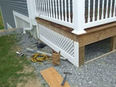 a wooden bench sitting on top of a gravel covered ground next to a white fence