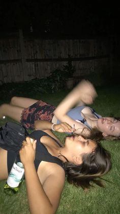 two young women laying on the grass together