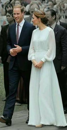 the duke and princess of cambridge walk together in front of a large group of people