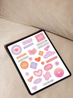 a close up of a tablet with stickers on it sitting on a couch next to a pillow