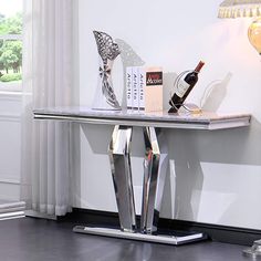 a silver table with some wine bottles and books on it in front of a window