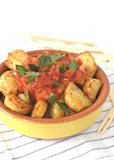 a yellow bowl filled with potatoes covered in marinara sauce