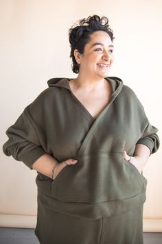 a woman with her arms on her hips, wearing a green dress and smiling at the camera