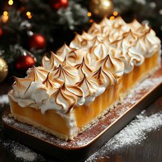 a piece of cake with whipped cream on top sits on a plate next to a christmas tree