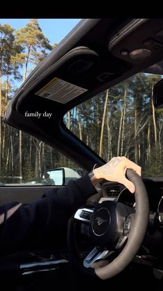 a person driving a car with the words family day written on the dashboard and trees in the background