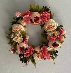 a floral wreath hanging on the wall with pink and red flowers in it's center