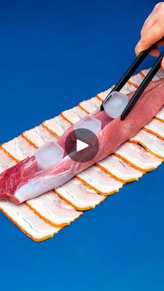 a person cutting meat with chopsticks on top of it in front of a blue background