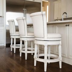 a kitchen with white chairs and wood flooring