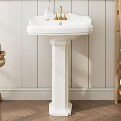 a white pedestal sink sitting next to a wooden chair in a room with wood flooring