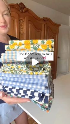 a woman holding stacks of cloths in her hands with the text, the easy way to tie a wreath sash?