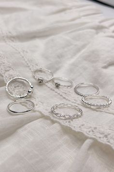 The Veronica Heart Ring Set is a charming collection of seven rings, available in silver or gold and sized at 7. This versatile set includes a variety of designs to suit any style: one ring features an open heart, two rings showcase rhinestone hearts, one plain band offers simplicity, one band is adorned with sparkling rhinestones, one chainlink band adds a unique touch, and one notched band completes the set. Perfect for mixing and matching, the Veronica Heart Ring Set is a delightful way to accessorize any outfit with a touch of love and elegance. Trendy Silver Heart Ring For Anniversary, Trendy Silver Heart Rings, Trendy Silver Heart-shaped Ring, Elegant Everyday Silver Heart Ring, Silver Heart-shaped Metal Ring, Trendy Silver Heart Promise Ring, Silver Trendy Heart Promise Ring, Trendy Silver Crystal Wedding Ring, Trendy Silver Crystal Ring For Wedding