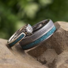 two wedding rings sitting on top of a rock next to each other with a diamond in the center