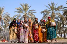 a group of women standing next to each other in front of trees and palm trees