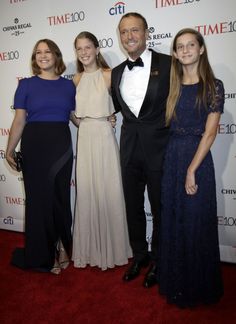 three women and a man standing on a red carpet