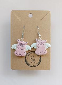 the earrings are shaped like pigs with angel wings