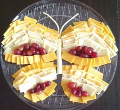 grapes and cheese are arranged on a glass platter with toothpicks in the middle