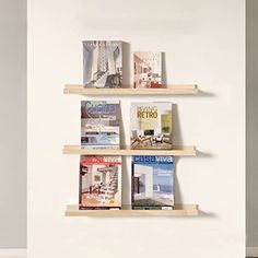 three wooden shelves with magazines on them against a white wall in a living room or bedroom