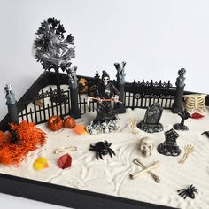 a table topped with halloween decorations and fake skeletons on top of sand covered in snow