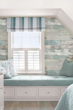 a bedroom with a window seat in front of the window and wooden planks on the wall