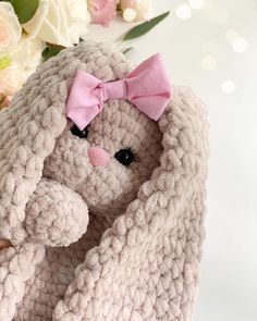 a crocheted stuffed animal with a pink bow on its head sitting next to flowers