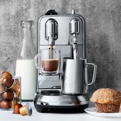 an espresso machine sitting on top of a counter next to a cup of coffee