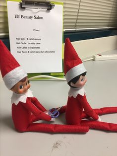 two elfs sitting on top of a desk next to a sign